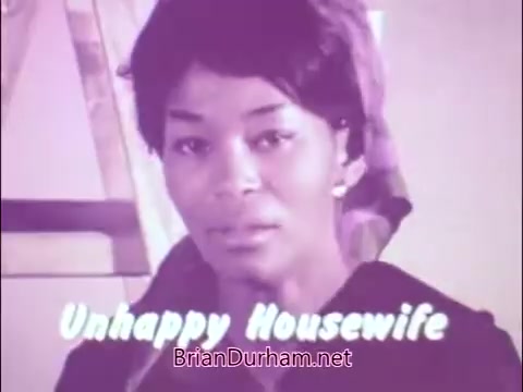 The still is from the 1960s/70s PSA 'A Matter of Life and Breath,' featuring James Noble as the 'Sad Commuter.' It highlights the struggles of individuals affected by respiratory diseases, aiming to raise awareness about tuberculosis and respiratory health. The tone is serious, reflecting the emotional impact of these conditions on daily life. The visual style is characteristic of the period, featuring muted colors and straightforward messaging.