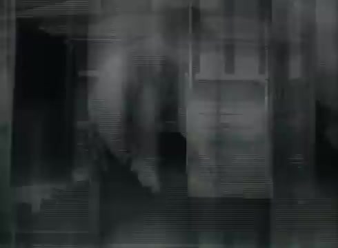 The still from 'Bell System Film - Drop Wire Runs Part 1 (b)' likely shows footage from a Central Office, illustrating the process of connecting telephone wires from utility poles to customers. It captures a historic moment in telecommunications, emphasizing technical details of wire installation. The visual quality reflects the era, possibly showing graininess or contrast typical of late 1940s to early 1950s films.