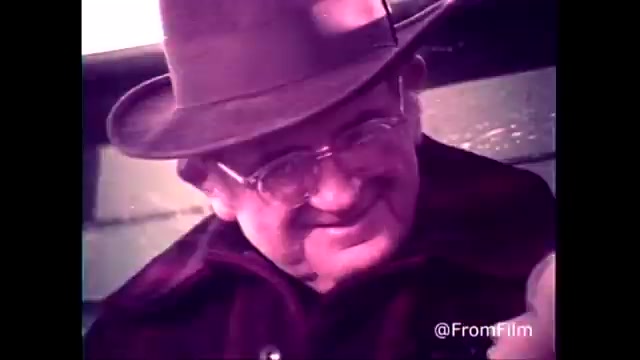 In this still from the 1970s C&P Telephone commercial, a warmly smiling older man wearing glasses and a hat is depicted, likely conveying a sense of warmth and connection. The background hints at a rural setting, typical of West Virginia, complementing the tagline, 'The next best thing to being there.' The post-1969 Bell System logo signifies the era of the ad. This imagery reflects the era's charm and promotes the reliability of telephone communication in connecting loved ones.