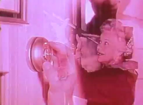 The still from 'Welcome to Fulton St' features a blend of visuals highlighting energy-efficient houses. A hand is shown adjusting a thermostat, symbolizing control over home energy use. The smiling woman, possibly a homeowner, conveys a positive attitude toward energy savings. The overall pink tint adds a nostalgic, retro feel to the scene, reinforcing the PSA's friendly and approachable message about energy efficiency.