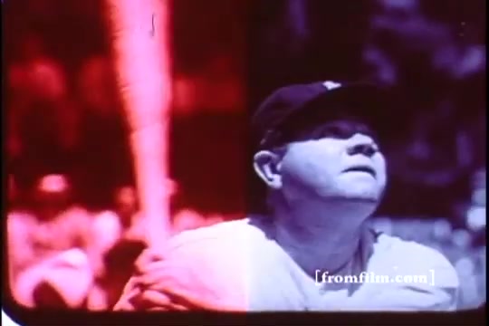 The still features a colorized image from a 16mm print of a 1970s Kellogg's Corn Flakes commercial, showcasing Babe Ruth. The scene is split, with one side displaying a reddish hue and the other side in more neutral tones. Babe Ruth is depicted holding a baseball bat, looking up, potentially anticipating a pitch or a dramatic moment in a game. The background includes blurred figures, suggesting an audience or players, enhancing the nostalgic and energetic atmosphere typical of baseball imagery.