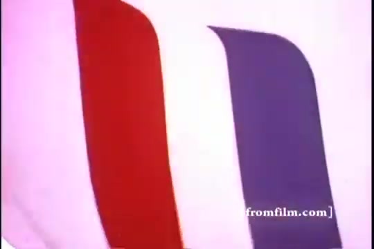 The still features a vibrant display of stripes in red, blue, and white, likely representing a visually dynamic advertisement backdrop. The context suggests a nostalgic 1970s theme associated with Kellogg's Corn Flakes, possibly alluding to themes of Americana and sports, notably with Babe Ruth. The colors and design evoke a playful and energetic atmosphere typical of that era's advertising style.