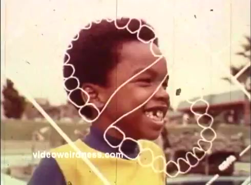 The still features a young boy smiling, wearing a bright yellow and blue outfit. The image has a playful, retro aesthetic typical of 1970s commercials. Overlaying the boy are whimsical graphics, possibly emphasizing a theme of joy or excitement, which may relate to the Dinah Shore Golf Tournament mentioned in the context. The overall vibe is cheerful and nostalgic.