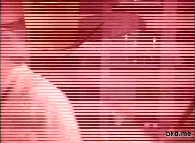The still features a scene from a 1960s-1970s television commercial for Spic and Span. The image is characterized by a pinkish tint and visible film grain, typical of 16mm prints. The focus appears to be on a person, partially visible, likely engaged in cleaning or showcasing the product, with household items in the background. The overall aesthetic reflects the era’s commercial style, emphasizing cleanliness and efficiency.
