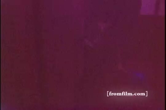 The still features a low-light scene with a blurred, somewhat abstract composition, typical of the 1970s commercial aesthetics, likely emphasizing the softness and appeal of Downy Fabric Softener. The colors may appear muted or diffused, creating a nostalgic ambiance associated with the era's advertisements.