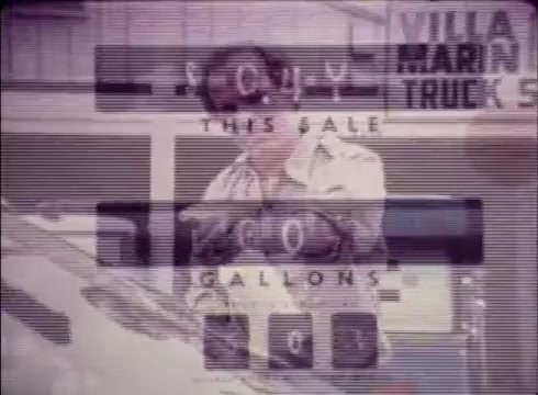 The still from the 16mm commercial for Job Service features a man interacting with a vehicle, likely emphasizing a job opening or service related to transportation or logistics. Text overlays suggest a sale or promotional offer. The scene likely promotes Job Service’s role in filling job vacancies, illustrating its utility for both employers and job seekers in Colorado. The overall aesthetic reflects the vintage style typical of public service announcements from that era.