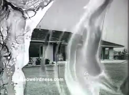 The still from 'Kaiser Aluminum - The Bright Idea' features a residential setting with a modern house in the background and a stark, organic abstract pattern overlay. The image reflects the themes of innovation and cost-effectiveness associated with Kaiser Aluminum, emphasizing its applications in enhancing everyday living. The visual suggests a blend of beauty and practicality, aligning with the slogan 'Better living at lower cost.'