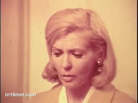 The still from the 'Puffs Tissues' commercial features a woman with blonde hair styled in soft waves, wearing a light-colored outfit. She appears contemplative or slightly emotional, suggesting a moment of tenderness or sensitivity often associated with the use of tissues. The warm color tone adds to the nostalgic feel of the scene.