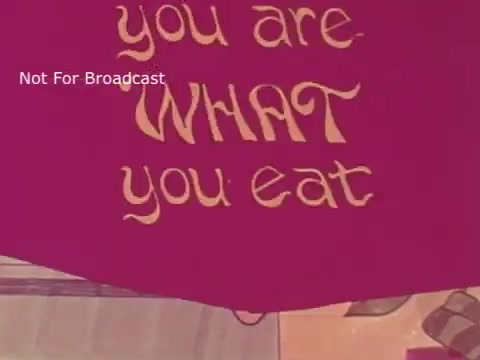 The still features the phrase 'you are WHAT you eat' prominently displayed in a playful, colorful font. The background suggests a school lunch theme, emphasizing the importance of food choices. The design reflects the vibrant, retro animation style typical of the 1970s, aiming to convey a message about healthy eating. The overlay text 'Not For Broadcast' indicates that this is not a publicly distributed image.