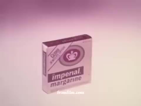 The still features a retro packaging of Imperial Margarine from the 1970s. The box is predominantly white with pink accents, displaying the brand name 'imperial' prominently. The design includes a crown logo, emphasizing a sense of quality. The overall aesthetic reflects the bold and simplistic style of advertising from that era.