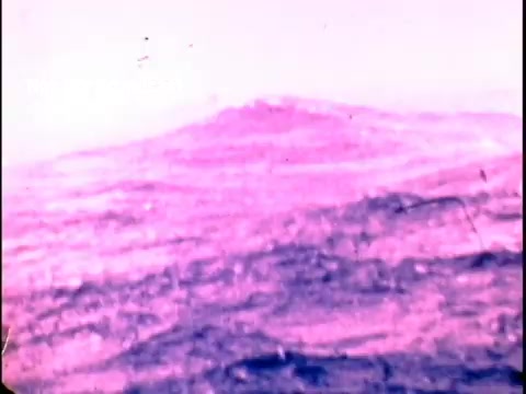 The still depicts a tumultuous ocean, showcasing large waves under a pale, possibly pinkish sky. The scene conveys a sense of chaos and danger, emphasizing the powerful impact of storm surge during hurricanes. The imagery is likely intended to highlight the hazards associated with severe weather events, aligning with the public safety message from FEMA and the National Weather Service.