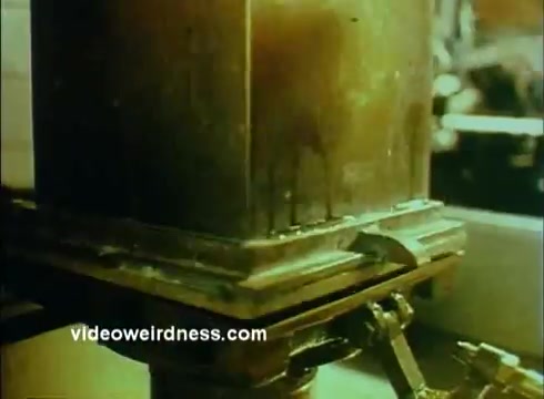 The still from the 'Sandoz Pharmaceuticals/Colors and Chemicals Commercial' showcases a close-up view of a large industrial machine in operation. The focus is on a metallic container or apparatus with visible residues, suggesting a process related to chemical production. The color palette is muted, indicative of the film's age, likely reflecting the industrial setting. The image conveys a sense of precision and functionality, aligning with the commercial's educational purpose.