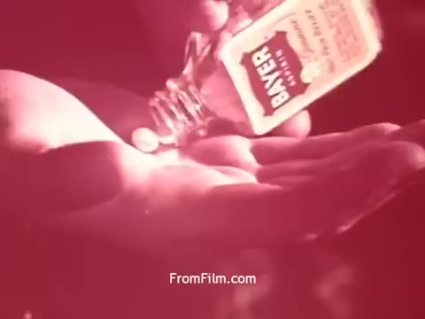 The still from 'Bayer Works Wonders' features a hand pouring a liquid from a small bottle labeled 'BAYER' into another hand. The scene is dominated by a warm, reddish hue, suggesting a focus on the product and its application. The tactile interaction emphasizes the personal nature of the product being promoted.