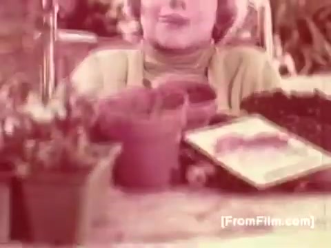 The 16mm still features a woman, likely portrayed by a well-known figure, seated in a wheelchair. She is surrounded by potted plants and gardening supplies, suggesting a theme of nurturing and growth. Her expression conveys warmth and encouragement, aligning with the message of the Muscular Dystrophy PSA, which is enhanced by Joan Crawford's voice-over, promoting awareness and support for individuals with the condition. The overall tone is hopeful and supportive.