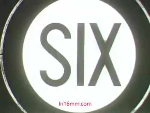The still from the 'Kukla and Ollie' pesticide PSA features a simple design with the word 'SIX' prominently displayed in bold letters against a circular background. This likely pertains to a countdown or important message related to the segment. The context involves Ollie expressing distress over his plant dying after using a pesticide, while Kukla questions his actions, highlighting the theme of awareness around pesticide use and its effects. The PSA aims to educate viewers on the proper use of such products.
