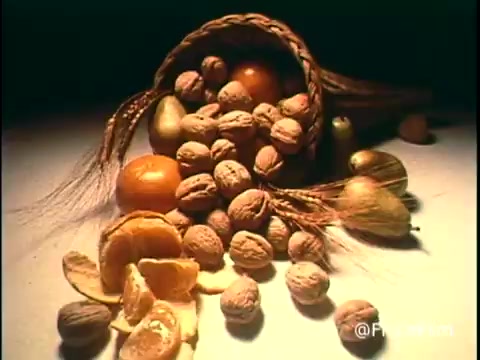 The still features a rustic arrangement of nuts spilling from a woven basket, with an emphasis on their natural textures and colors. Various nuts, including walnuts and pistachios, are scattered across a softly lit surface, creating a warm and inviting atmosphere. The composition evokes a sense of abundance and highlights the allure of snacking on Diamond Nuts. The vintage 16mm print adds a nostalgic quality to the image.   Follow us on Twitter @FromFilm.