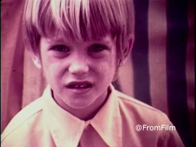 The still from the 1970 PSA 'Why do you think they call it dope?' features a young boy with a serious expression, emphasizing the gravity of the anti-drug message. He has short, light-colored hair and wears a collared shirt. The background shows muted colors, possibly striped, creating a stark contrast to his concerned face. The image encapsulates the emotional weight of the campaign, aiming to provoke reflection on the dangers of drug use.   .