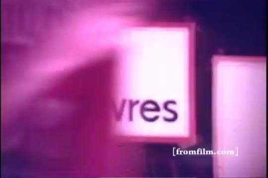 The still appears to capture a moment from the 1971 Old Milwaukee Beer commercial featuring Bernie Kopell. It features a blurred motion effect alongside signs, suggesting a lively atmosphere typical of vintage commercials. The overall tone is nostalgic, evoking the style and charm of early 70s advertising.