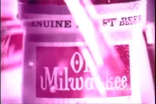 The still from the 1971 Old Milwaukee Beer commercial features a close-up of the beer can prominently displaying the brand's logo. The image is in vivid colors, likely with a pinkish hue, suggesting a lively atmosphere. Bernie Kopell, a well-known actor, is associated with the ad but isn’t visible in this particular frame. The focus is on the can, emphasizing the product's nostalgic appeal.
