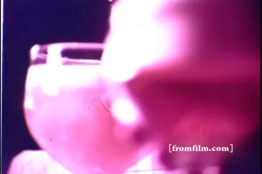 The still from the 1971 Old Milwaukee Beer commercial features a close-up of a glass of beer, possibly golden in color, with the focus on the drink rather than any visible characters. The scene has a vintage quality typical of 16mm film, showcasing soft lighting and subtle flaws characteristic of older prints. A human figure may be partially visible, suggesting a celebratory or casual atmosphere.