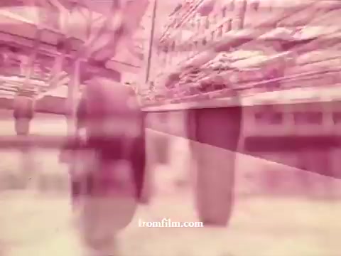 The still from 'Chatham Supermarket Commercials' features a blurred perspective, possibly of grocery carts rolling through an aisle. The color palette appears faded, giving it a vintage look characteristic of 16mm prints. Key themes might include fresh produce like apples and bananas, a comparison of products, coupons, and various meats including fresh cuts and steak. Overall, it evokes a nostalgic feel of supermarket shopping.