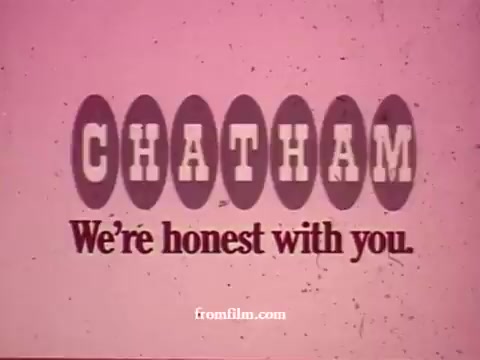 The still from the 'Chatham Supermarket Commercials' features the store's logo prominently, with bold colors and a playful font. It conveys a reassuring message with the tagline 'We're honest with you.' The context implies a focus on various grocery items such as apples, bananas, meats, and potatoes, showcasing the supermarket's commitment to freshness and value through comparisons and coupons. The vintage 16mm aesthetic adds a nostalgic feel to the advertisement.