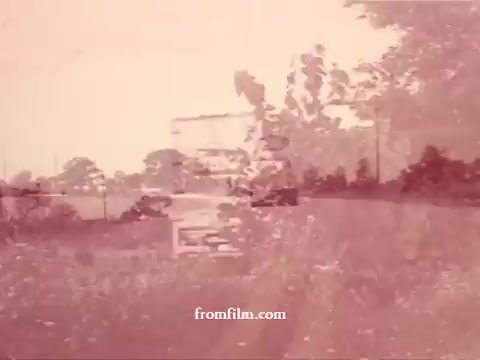 The 16mm still from 'Chatham Supermarket Commercials' features a vintage scene, likely showcasing a supermarket environment. The frame is washed in soft, faded tones, hinting at age, with outlines of carts and possibly a display of fresh produce like apples and bananas. Elements of comparison and coupon offers suggest a focus on promotional content. The inclusion of fresh cut meats and potatoes indicates a variety of grocery items being highlighted. Overall, it evokes a nostalgic atmosphere of shopping in a mid-20th century supermarket.