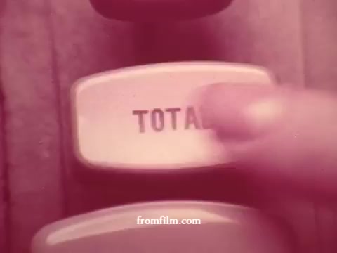 The still features a close-up of a finger pressing the 'TOTAL' button on a vintage cash register. The color tones suggest a retro or nostalgic style, typical of 16mm film. The context involves supermarket commercials from Chatham, highlighting various products such as apples, bananas, meats, and coupons, likely emphasizing the store's value and freshness.