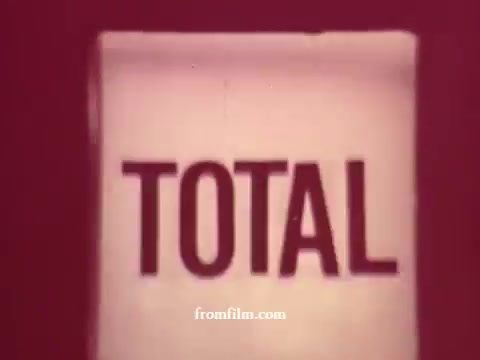 The still from 'Chatham Supermarket Commercials' features a prominent display of the word 'TOTAL.' This suggests a focus on pricing or savings, likely emphasizing the value of grocery items such as apples, bananas, meats, and steak. The visual presentation is characteristic of vintage advertising, highlighting a variety of supermarket offerings.