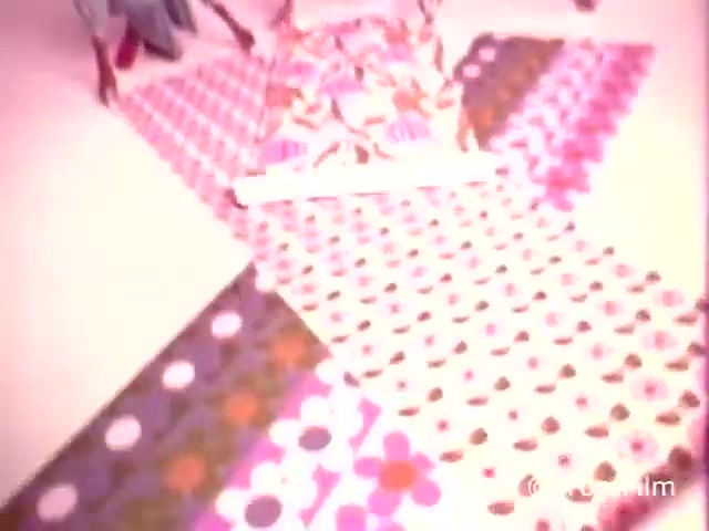 The still features a vibrant, patterned display of Kleenex Boutique Tissues from the 1970s, showcasing bold designs typical of that era. The colors are bright and eclectic, with floral and polka dot motifs. This promotional piece emphasizes the decorative aspect of tissues, linking them to a stylish lifestyle. The overall aesthetic evokes a nostalgic sentiment for the design trends of the 1970s.