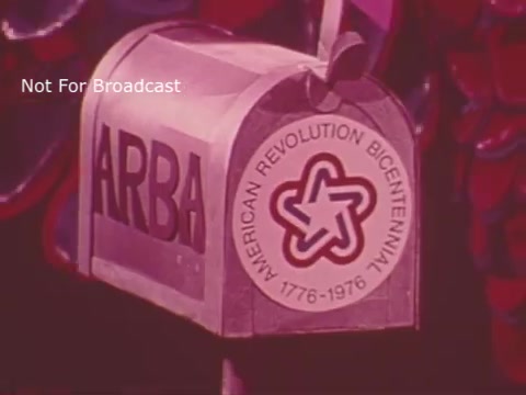 The still features a stylized mailbox with 'ARBA' written on it, alongside a logo for the American Revolution Bicentennial, indicating the theme of the 1976 Spanish USA Bicentennial commercial. The design is vibrant and colorful, reflecting the celebratory spirit of the event.