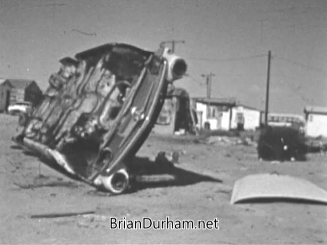 The still from the VISTA PSA depicts an abandoned, overturned car in a desolate area, highlighting the social and economic challenges addressed by the Volunteers in Service to America program. Surrounding the vehicle are rundown structures, emphasizing the urgency of combating poverty and the need for community engagement and support in such environments. The image serves as a stark reminder of the realities faced by many in the War on Poverty initiative launched in the 1960s.