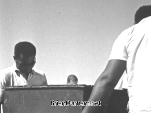 The still from the 1960s PSA for Volunteers in Service To America (VISTA) depicts a group of individuals actively engaged in work related to community service. They appear focused and collaborative, embodying the spirit of the anti-poverty initiative launched under Lyndon Johnson’s Economic Opportunity Act. The scene highlights their commitment to making a tangible difference in the fight against poverty. The black-and-white format reflects the era and contributes to its historical context.