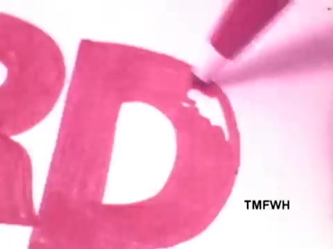 The still from the Flair Pen commercial shows a close-up of a vibrant pink marker in the process of coloring in a large letter 'D' on white paper. The focus emphasizes the smooth, fluid motion of the pen, showcasing its bold ink and promoting its writing quality. The background is minimal, drawing attention to the pen's performance and the vivid color.