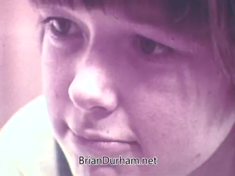 The still from 'Ideal 'Up Set' game - 1973' features a close-up of a child's face, capturing a moment of focus and concentration. The soft colors and vintage aesthetic suggest a nostalgic feel, typical of the 1970s. The child appears engaged, possibly contemplating a game or activity related to the 'Up Set' theme.