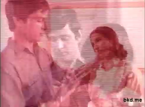 The still shows two main characters—a young man and a woman—interacting in a domestic setting, likely promoting Duz soap. The background has a slightly blurred image of another man's face, contributing to a layered effect. The color scheme is soft with a slight vintage tint, typical of 16mm film, possibly giving a nostalgic quality to the commercial.