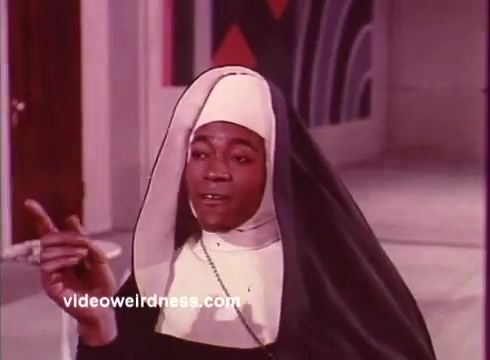 In this still from 'Come Back, Charleston Blue,' we see a character dressed as a nun, suggesting a blend of religious and comedic elements typical of the film's blaxploitation genre. The vibrant color palette and stylized background reflect the film's unique aesthetic, while the character's expressive gesture suggests a humorous or lively moment. The scene likely highlights themes of identity and society, consistent with the film's exploration of urban life and social issues, rooted in Chester Himes' work.