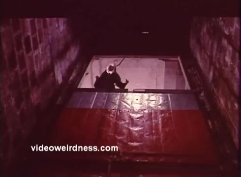 The still from *Come Back, Charleston Blue* features a dimly lit scene focused on a character standing in an underground setting. The character appears to be in a crouched position, creating a sense of tension. The colors in the scene suggest a gritty atmosphere typical of blaxploitation films, with shadows enhancing the mysterious vibe. This sequel continues the story of Coffin Ed Johnson and Gravedigger Jones, highlighting themes of crime and perseverance within the African American community. The film captures the essence of urban struggles through its characters and narrative.