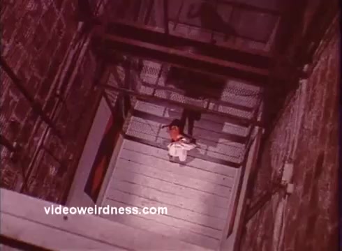 The still from *Come Back, Charleston Blue* depicts a dramatic downward view of a figure on a staircase, likely implying a tense moment. The film, part of the blaxploitation genre, continues the stories of Coffin Ed Johnson and Gravedigger Jones, two iconic characters created by Chester Himes. The atmospheric lighting and framing contribute to the gritty and intense aesthetic characteristic of this era of cinema. This scene likely encapsulates the film's themes of social struggle and urban life.