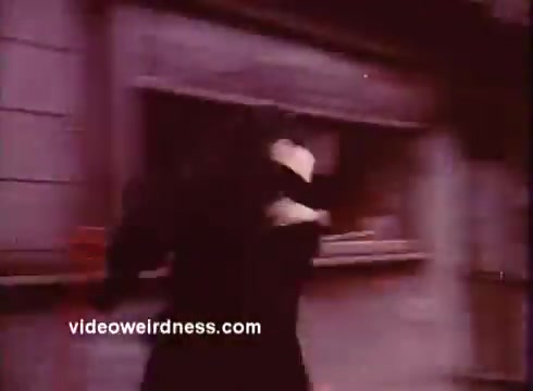 The 16mm still from *Come Back, Charleston Blue* depicts a scene with a figure running, likely in a moment of urgency or action. The color palette has a vintage, somewhat muted quality typical of films from the 1970s, contributing to the blaxploitation aesthetic. This film continues the narrative of Coffin Ed Johnson and Gravedigger Jones, characters inspired by Chester Himes' works, highlighting themes of crime and community in Harlem. The context of the film reflects the cultural dynamics and social issues of its time, using a blend of humor and drama.