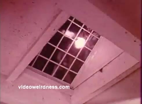 The still from 'Come Back, Charleston Blue' depicts a dimly lit scene featuring a grid-patterned vent or grate with a light source shining from above. The surrounding area appears to have a rustic or industrial feel, hinting at the gritty atmosphere typical of blaxploitation films. This scene likely contributes to the film's exploration of themes such as crime and social issues, characteristic of the works of Chester Himes. The film follows characters Coffin Ed Johnson and Grave Digger Jones as they navigate the challenges of their environment.