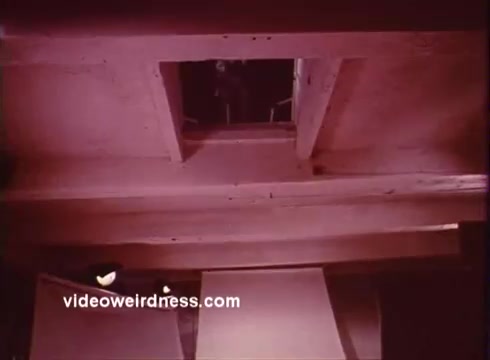 The still from 'Come Back, Charleston Blue' features an overhead view, possibly of a set or location used in the film. The warm pink tones dominate the image, suggesting a stylized aesthetic typical of the blaxploitation genre. The opening in the ceiling may indicate a point of tension or drama, common in the narrative's exploration of crime and social issues. The film, starring Godfrey Cambridge and Raymond St. Jacques, continues the story of Coffin Ed Johnson and Gravedigger Jones, characters inspired by Chester Himes' work.