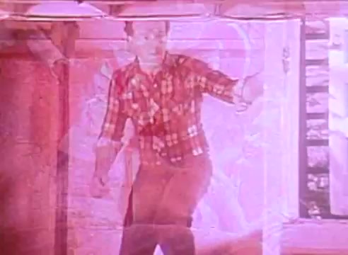 The still from 'Welcome to Fulton St' features a man stepping through a doorway, wearing a checkered shirt. The image has an overlay effect, giving it a slightly surreal and tinted quality. The context suggests a focus on energy-efficient housing, highlighting the man's engagement with the environment around him.