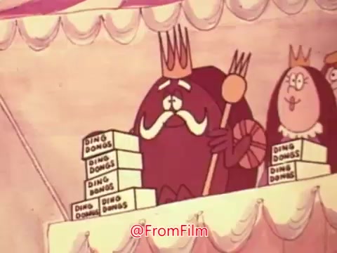 The still features animated characters from a Hostess Ding Dong commercial. A central figure, resembling a king, has a large mustache and holds a scepter. Next to him is another character, both situated behind a stack of Hostess Ding Dong boxes. The setting is colorful and whimsical, typical of animated advertisements from the time.