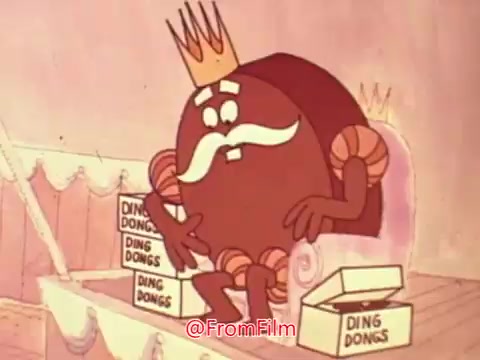 The still features a cartoon character resembling a chocolate treat, adorned with a crown and a mustache, sitting on a throne. Surrounding him are boxes of Hostess Ding Dongs, emphasizing the product's presence. The character appears to be pondering or gesturing, contributing to a playful and whimsical atmosphere typical of classic commercials. The pastel background adds to the lighthearted charm of the scene.