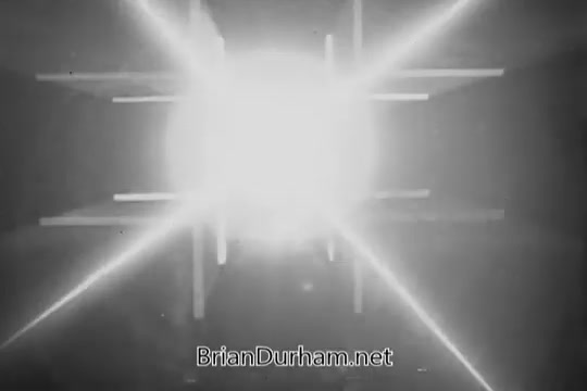 The still features a bright light source at the center, radiating beams and reflections, creating a dynamic and energetic atmosphere. The background appears abstract and layered, with lines intersecting around the focal point, typical of vintage commercial aesthetics. This reflects the lively and engaging style often used to promote products like cigars in that era.