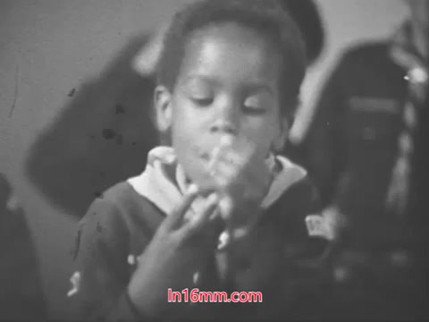 The still from the 1968 PSA features a young boy, likely a Cub Scout, engaged in an activity. He appears focused as he plays with something in his hands. The backdrop suggests a group setting, likely involving other Scouts. The overall tone is one of enjoyment and camaraderie, reflecting the fun and learning experiences associated with being a Cub Scout.