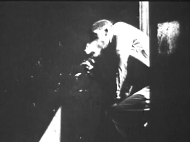 The still from the 'Ad Council PSA - Presidents Council on Youth Opportunity' features a man leaning against a wall or a doorframe, seemingly deep in thought. The image is in black and white, emphasizing the contrast and the emotional weight of the scene. The lighting suggests a somber or reflective mood, with shadows playing a significant role in the composition. The man appears focused on something outside the frame, evoking a sense of contemplation or longing.