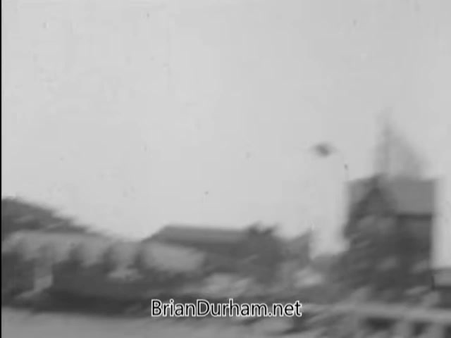 The still from 'A Matter of Life and Breath' (1968) depicts a scene with a flagpole sitter, focusing on themes of fear and anxiety about germs. The context suggests a critique of societal behaviors or quirks, emblematic of the time. The image captures a moment of tension and uncertainty, reflective of the individual's precarious position. The overall tone and visuals likely evoke a sense of vulnerability amidst a broader commentary on health and modern life.