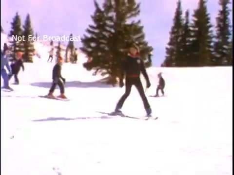 The still features a snowy landscape with several people skiing or snowboarding among evergreen trees. A clear blue sky is visible, indicating a sunny day. The bright colors and vibrant scene convey a sense of winter sports enjoyment. The overlay text indicates that it is not intended for broadcast.